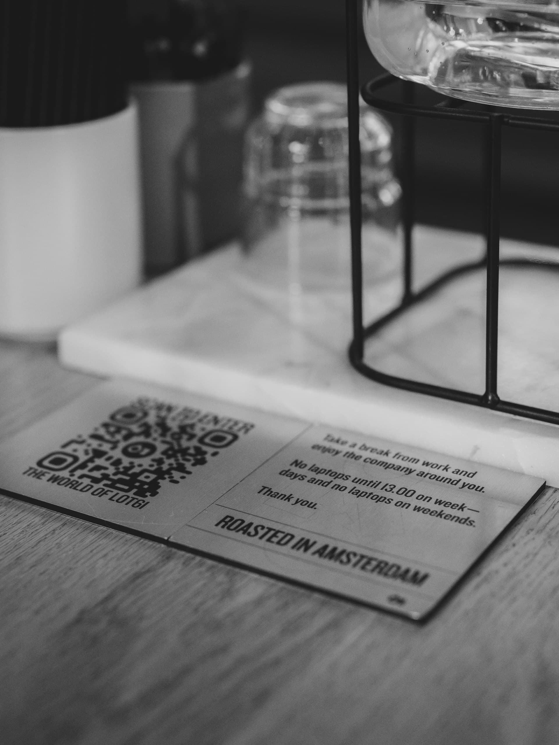 كارت table tent مطبوع عليه كود QR واسم المطعم، مفروض على ترابيزة كافيه خشب