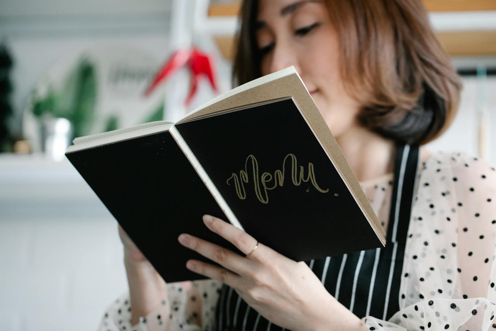 Phone showing a luxury restaurant PDF menu mid-page-flip with brand illustration visible
